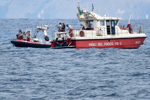 Italian Firefighters scuba divers bring ashore in a green bag the body of one of the victims of the sinking on Aug. 21.