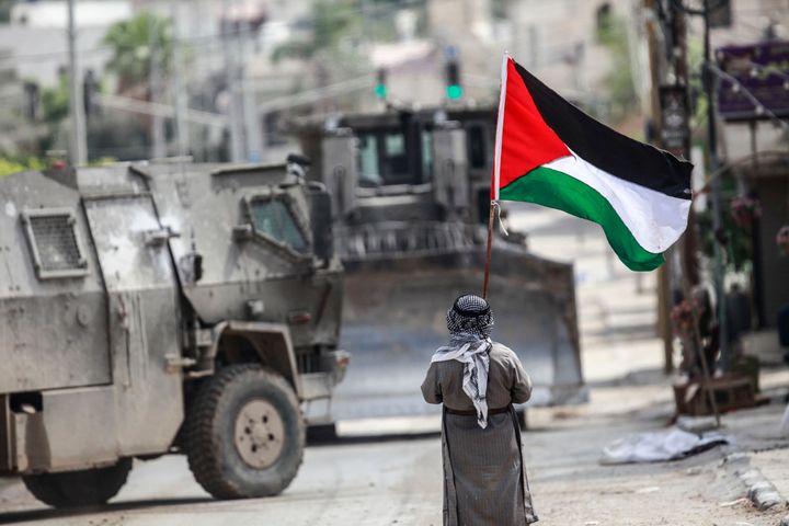 An elderly Palestinian man faces an Israeli military vehicle while holding a Palestinian flag, during a military raid on Tulkarm refugee camp in the northern occupied West Bank.