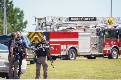 Officers hold guns while talking outside Apalachee High School on Wednesday following a shooting that left four people dead.