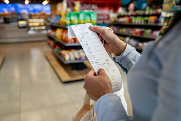 Close-up on a woman shopping at a convenience store and checking her receipt while exiting