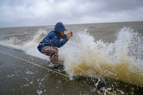 Conrad Bach gets doused with lake water while looking at waves from the wind and rain from Hurricane Francine along Lakeshore Drive along Lake Ponchartrain in New Orleans, on Sept. 11, 2024.