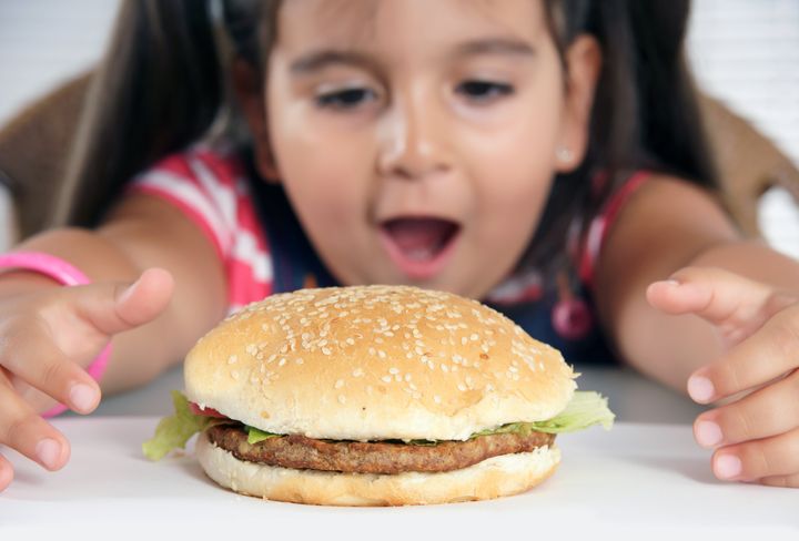 little caucasian girl eating burger