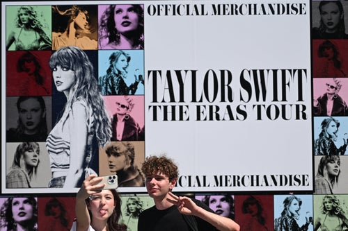 Taylor Swift fans take photos in front of her official merchandise during a stop on her Eras Tour in Warsaw, Poland, on July 31.
