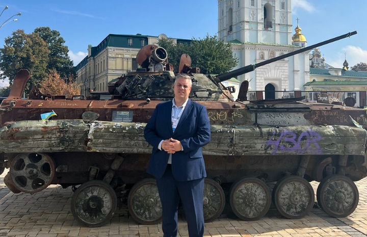 Blair McDougall beside a destroyed Russian tank in Kyiv.