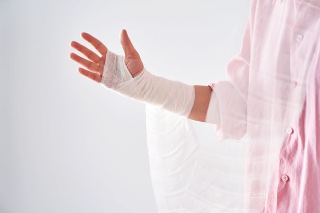 A woman in a pink shirt holds a bandage and puts a bandage on her arm. High quality photo.