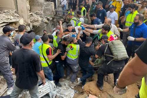 Rescuers carry a body at the scene of a missile strike in the southern suburbs of Beirut, Friday, Sept. 20, 2024. (AP Photo/Bilal Hussein)