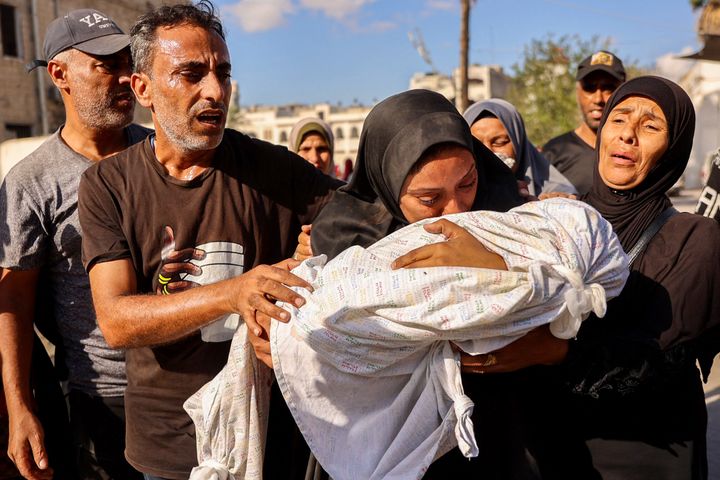 A woman mourns as she holds the shrouded body of her child who was killed during an Israeli strike on a school housing displaced Palestinians in Gaza City's Zaytoun neighborhood on September 21, 2024.