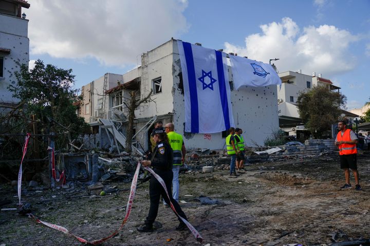 Municipal workers hang an Israeli flag on a damaged building that was hit by a rocket fired from Lebanon, in Kiryat Bialik, northern Israel, Sunday, Sept. 22, 2024. (AP Photo//Ariel Schalit)