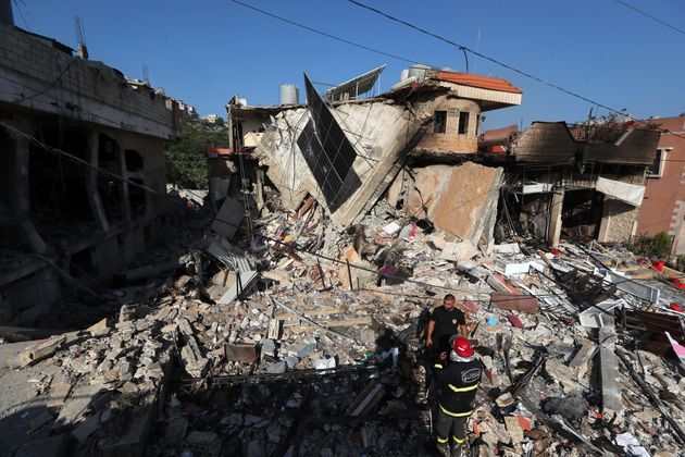 Rescuers stand on the rubble of a building hit in an Israeli airstrike in the southern village of Akbieh, Lebanon, Tuesday, Sept. 24, 2024.