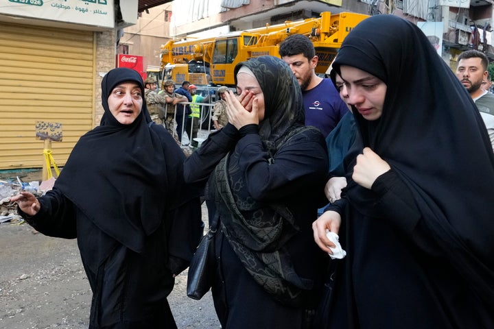 Residents cry as they walk past a building that was hit by an Israeli airstrike in Beirut's southern suburbs, on Sept. 24, 2024.