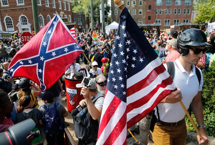 Weiße nationalistische Demonstranten gehen am Samstag, 12. August 2017, umgeben von Gegendemonstranten durch Lee Park in Charlottesville, Virginia. (AP Photo/Steve Helber, Datei)