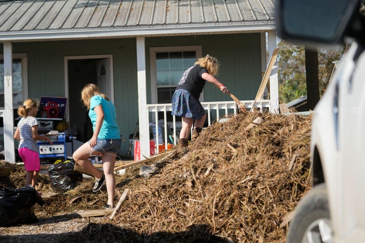 Die Familie Steen sammelt am Samstag verrotteten Müll aus Algenhaufen, die der Sturm zu ihrem Haus in Steenhatchee, Florida, getragen hat.