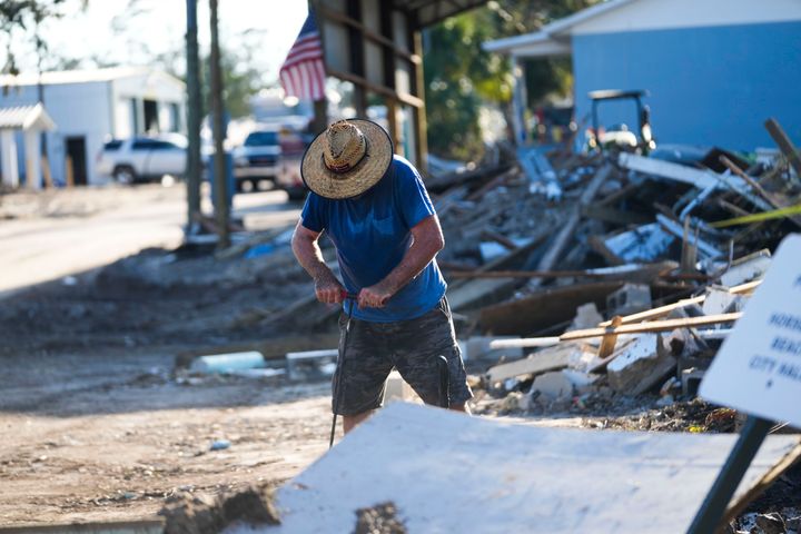 Der Wartungsleiter von Horseshoe Beach, Chris Jordan, versucht am Sonntag, den 29. September 2024, in Horseshoe Beach, Florida, in den Trümmern des nach Hurrikan Helen zerstörten Rathauses ein Ventil zu finden, um das Wasser abzusperren. (AP Photo/Gerald Herbert)