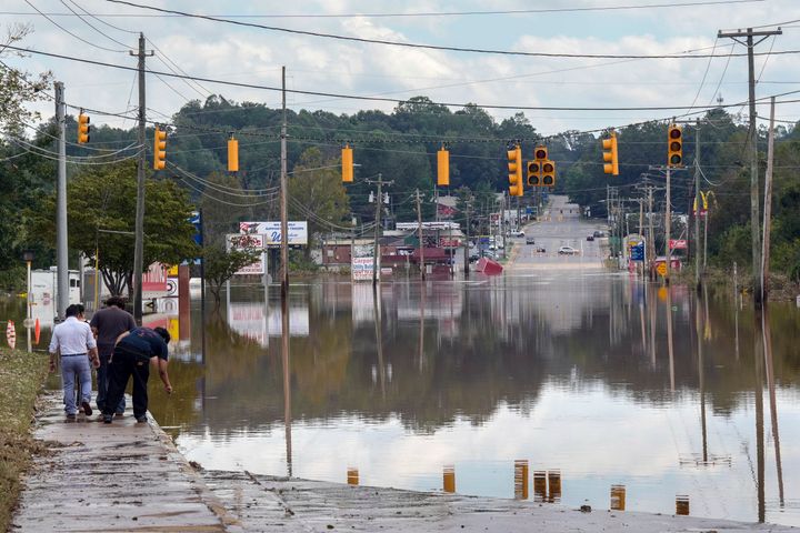 Ein Passant überprüft am Samstag, 28. September 2024, in Morganton, North Carolina, die Wassertiefe einer überfluteten Straße. Heftige Regenfälle durch Hurrikan Helen überschwemmten viele Straßen in der Gegend. Darüber hinaus waren Ampeln aufgrund von Stromausfällen sowie umgestürzten Stromleitungen und Bäumen außer Betrieb. (AP Photo/Kathy Kmonicek)