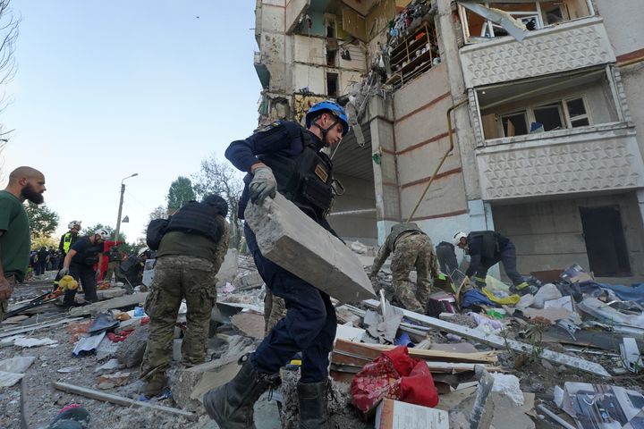 Emergency workers and soldiers try to shift the rubble and debris after a Russian attack that hit a residential building in Kharkiv.