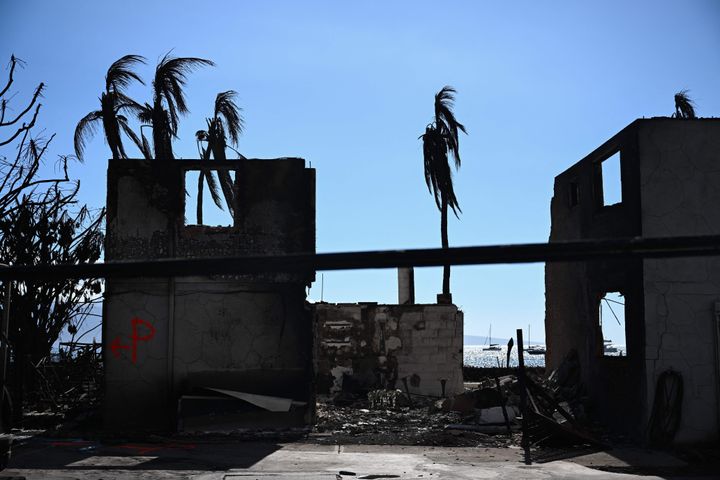 Spray paint marks a wall from a search and rescue team outside a burnt home as boats rest on the Pacific Ocean near Front Street in the aftermath of a wildfire in Lahaina, western Maui, Hawaii on August 11, 2023. A wildfire that left Lahaina in charred ruins has killed at least 67 people, authorities said on August 11, making it one of the deadliest disasters in the US state's history. Brushfires on Maui, fueled by high winds from Hurricane Dora passing to the south of Hawaii, broke out August 8 and rapidly engulfed Lahaina. (Photo by Patrick T. Fallon / AFP) (Photo by PATRICK T. FALLON/AFP via Getty Images)