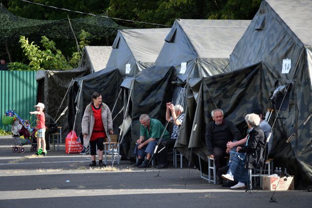 People evacuated from a fighting between Russian and Ukrainian forces in Kursk region sit next to tents at a temporary residence centre in Kursk, Russia, Monday, Aug. 12, 2024.