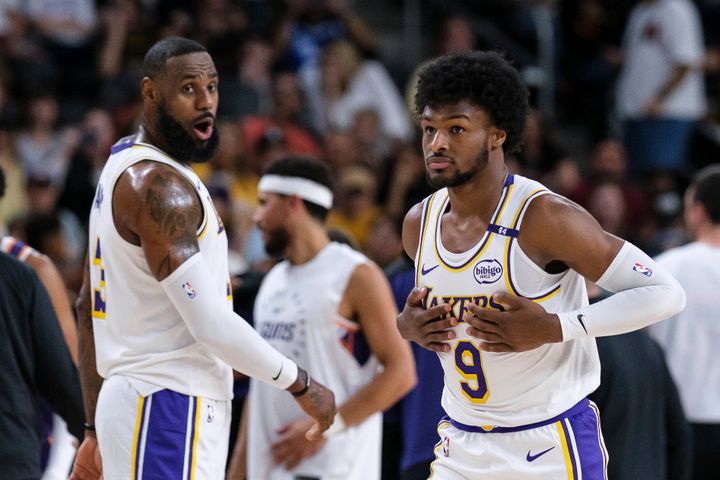 Los Angeles Lakers guard Bronny James (9), right, steps onto the court with Los Angeles Lakers forward LeBron James (23) during the first half of a preseason NBA basketball game Sunday, Oct. 6, 2024, in Palm Desert, Calif. (AP Photo/William Liang)