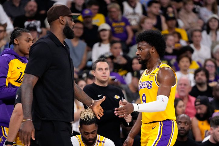 Los Angeles Lakers' LeBron James, left, greets his son, Bronny James as Bronny comes off the court during the first half of a preseason NBA basketball game, Friday, Oct. 4, 2024, in Palm Desert, Calif. (AP Photo/Mark J. Terrill)