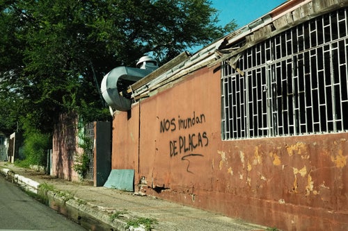 Graffiti reading "They're drowning us in panels" on a building in the El Coquí neighborhood of Salinas, Puerto Rico, which has seen increased flooding since construction began on a large-scale solar farm next door.