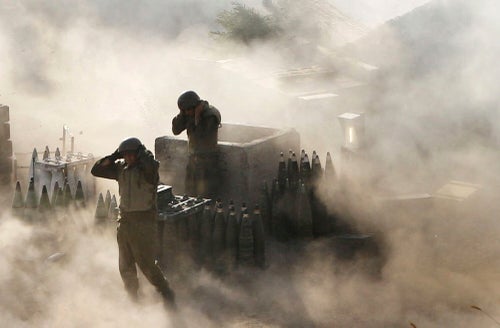Israeli soldiers are surrounded by smoke and dust as they fire across the border into southern Lebanon from the frontier in Zaura, northern Israel, on July 12, 2006.