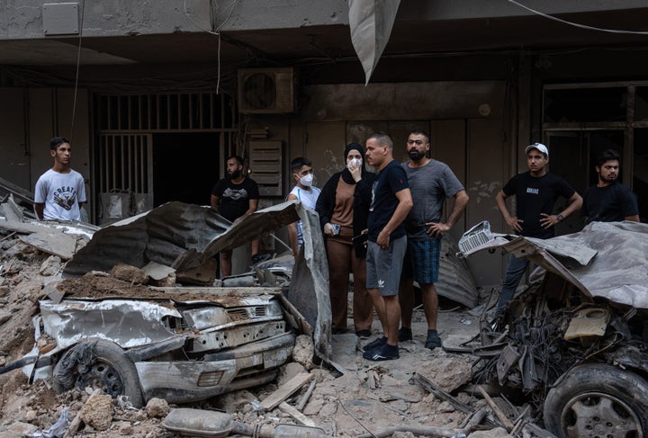 Local residents stand behind ruined vehicles as they watch rescue workers search through the rubble of a building hit by an Israeli airstrike on October 11, 2024 in Beirut, Lebanon. (Photo by Carl Court/Getty Images)