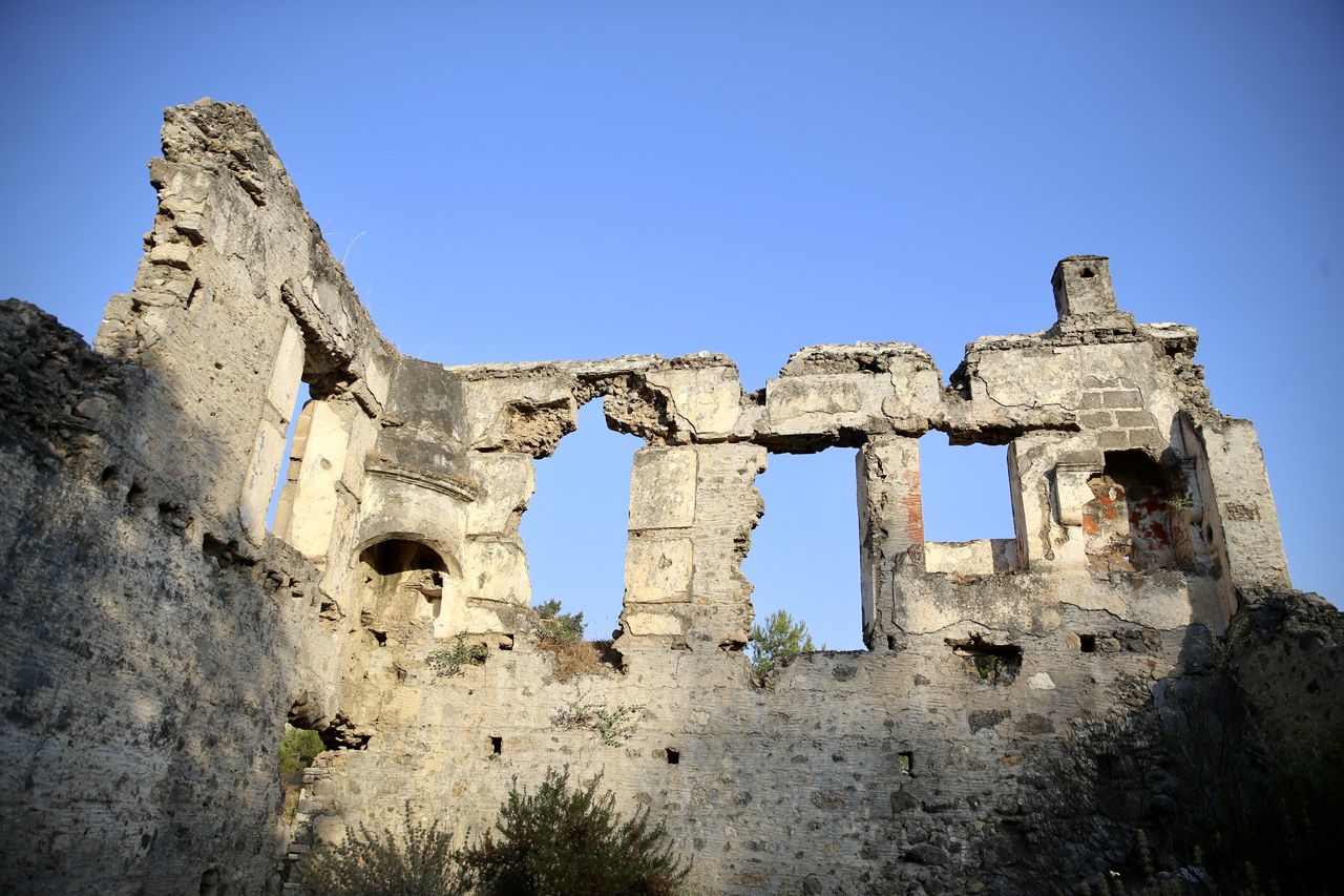 MUGLA, TURKIYE - JUNE 25: A view of Kayakoy, which is also known as a 'ghost town' because it was abandoned years ago and is among the sensitive areas to be strictly protected in Fethiye district of Mugla, Turkiye on June 25, 2024. Kayakoy, or Levissi in Greek, is a village in Fethiye in southwestern Turkiye where Anatolian Greeks lived until approximately 1923. The ghost town, now preserved as a museum village, consists of hundreds of rundown but still mostly intact Greek-style houses and churches which cover a small mountainside and serve as a stopping place for tourists visiting Fethiye and nearby Oludeniz. It was built on the site of the ancient city of Carmylessus in the 1700s. After the Greek-Turkish War, Kayakoy was largely abandoned after a population exchange agreement was signed by the Turkish and Greek governments in 1923. (Photo by Ali Riza Akkir/Anadolu via Getty Images)