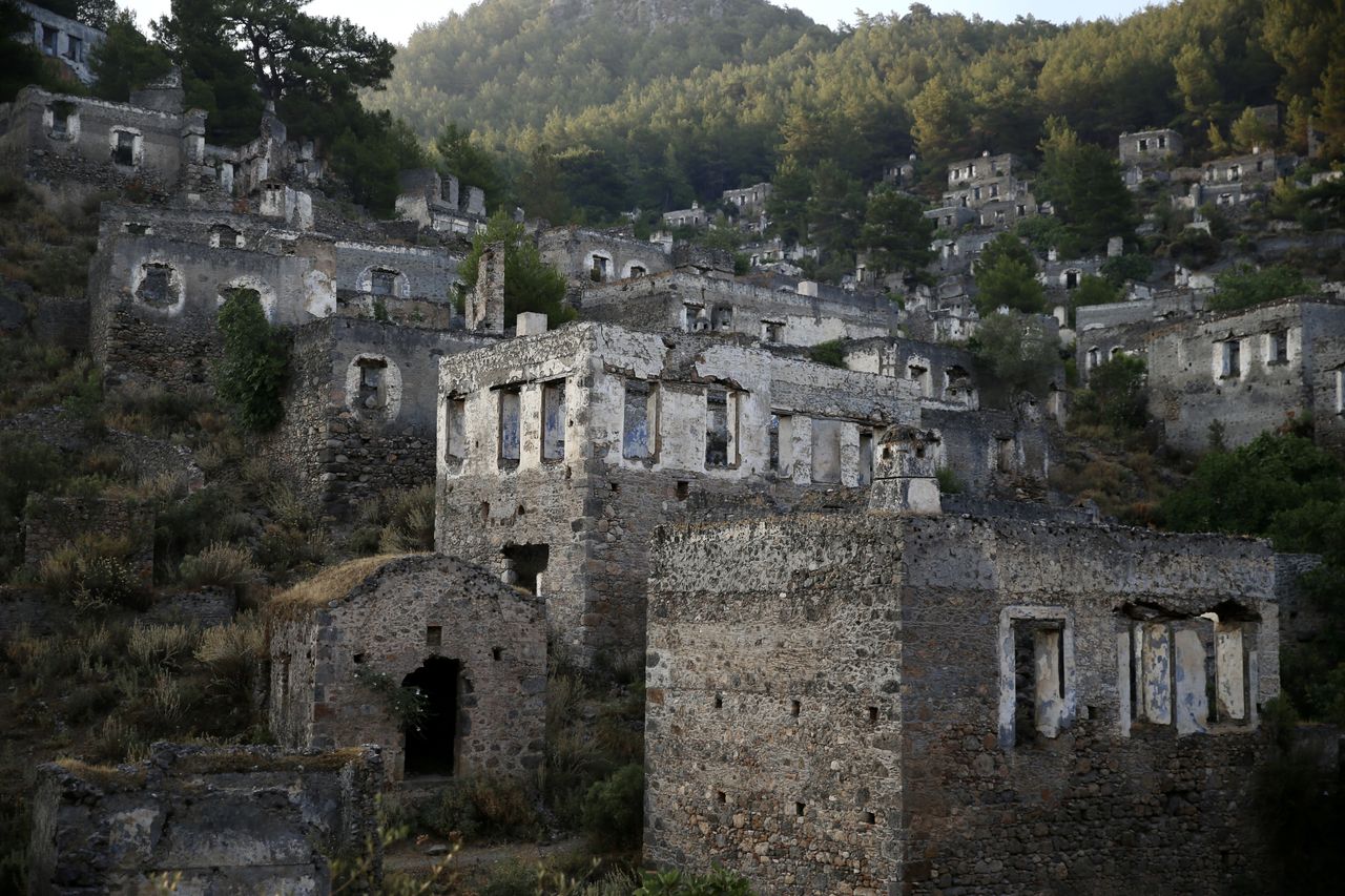 MUGLA, ΤΟΥΡΚΙΑ - 25 ΙΟΥΝΙΟΥ: Άποψη του Kayakoy, το οποίο είναι επίσης γνωστό ως "πόλη-φάντασμα" επειδή εγκαταλείφθηκε πριν από χρόνια και συγκαταλέγεται στις ευαίσθητες περιοχές που πρέπει να προστατευθούν αυστηρά στην περιοχή Fethiye της Mugla, στην Τουρκία, στις 25 Ιουνίου 2024. Το Kayakoy, ή Levissi στα ελληνικά, είναι ένα χωριό στο Fethiye της νοτιοδυτικής Τουρκίας όπου ζούσαν Έλληνες της Ανατολίας μέχρι περίπου το 1923. Η πόλη-φάντασμα, που σήμερα διατηρείται ως μουσειακό χωριό, αποτελείται από εκατοντάδες ετοιμόρροπα αλλά ακόμα ως επί το πλείστον άθικτα σπίτια και εκκλησίες ελληνικού τύπου, τα οποία καλύπτουν μια μικρή βουνοπλαγιά και χρησιμεύουν ως σημείο στάσης για τους τουρίστες που επισκέπτονται το Φετιγιέ και το κοντινό Ολουντενίζ. Χτίστηκε στη θέση της αρχαίας πόλης Καρμυλέσσου τη δεκαετία του 1700. Μετά τον ελληνοτουρκικό πόλεμο, το Καγιάκοϊ εγκαταλείφθηκε σε μεγάλο βαθμό μετά την υπογραφή συμφωνίας ανταλλαγής πληθυσμών από την τουρκική και την ελληνική κυβέρνηση το 1923. (Φωτογραφία: Ali Riza Akkir/Anadolu via Getty Images)