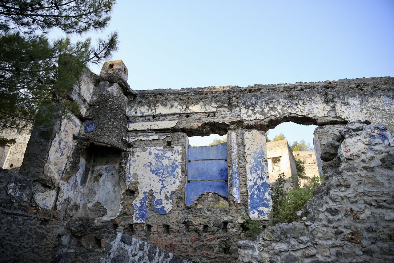 MUGLA, ΤΟΥΡΚΙΑ - 25 ΙΟΥΝΙΟΥ: Άποψη του Kayakoy, το οποίο είναι επίσης γνωστό ως "πόλη-φάντασμα" επειδή εγκαταλείφθηκε πριν από χρόνια και συγκαταλέγεται στις ευαίσθητες περιοχές που πρέπει να προστατευθούν αυστηρά στην περιοχή Fethiye της Mugla, στην Τουρκία, στις 25 Ιουνίου 2024. Το Kayakoy, ή Levissi στα ελληνικά, είναι ένα χωριό στο Fethiye της νοτιοδυτικής Τουρκίας όπου ζούσαν Έλληνες της Ανατολίας μέχρι περίπου το 1923. Η πόλη-φάντασμα, που σήμερα διατηρείται ως μουσειακό χωριό, αποτελείται από εκατοντάδες ετοιμόρροπα αλλά ακόμα ως επί το πλείστον άθικτα σπίτια και εκκλησίες ελληνικού τύπου, τα οποία καλύπτουν μια μικρή βουνοπλαγιά και χρησιμεύουν ως σημείο στάσης για τους τουρίστες που επισκέπτονται το Φετιγιέ και το κοντινό Ολουντενίζ. Χτίστηκε στη θέση της αρχαίας πόλης Καρμυλέσσου τη δεκαετία του 1700. Μετά τον ελληνοτουρκικό πόλεμο, το Καγιάκοϊ εγκαταλείφθηκε σε μεγάλο βαθμό μετά την υπογραφή συμφωνίας ανταλλαγής πληθυσμών από την τουρκική και την ελληνική κυβέρνηση το 1923. (Φωτογραφία: Ali Riza Akkir/Anadolu via Getty Images)