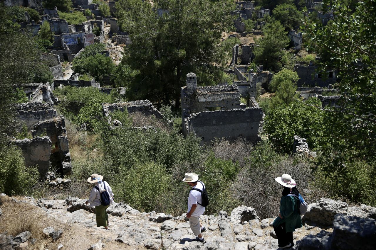 MUGLA, ΤΟΥΡΚΙΑ - 25 ΙΟΥΝΙΟΥ: Άνθρωποι επισκέπτονται το Kayakoy, το οποίο είναι επίσης γνωστό ως "πόλη-φάντασμα" επειδή εγκαταλείφθηκε πριν από χρόνια και συγκαταλέγεται στις ευαίσθητες περιοχές που πρέπει να προστατευθούν αυστηρά στην περιοχή Fethiye της Mugla, Τουρκία, στις 25 Ιουνίου 2024. Το Kayakoy, ή Levissi στα ελληνικά, είναι ένα χωριό στο Fethiye της νοτιοδυτικής Τουρκίας όπου ζούσαν Έλληνες της Ανατολίας μέχρι περίπου το 1923. Η πόλη-φάντασμα, που σήμερα διατηρείται ως μουσειακό χωριό, αποτελείται από εκατοντάδες ετοιμόρροπα αλλά ακόμα ως επί το πλείστον άθικτα σπίτια και εκκλησίες ελληνικού τύπου, τα οποία καλύπτουν μια μικρή βουνοπλαγιά και χρησιμεύουν ως σημείο στάσης για τους τουρίστες που επισκέπτονται το Φετιγιέ και το κοντινό Ολουντενίζ. Χτίστηκε στη θέση της αρχαίας πόλης Καρμυλέσσου τη δεκαετία του 1700. Μετά τον ελληνοτουρκικό πόλεμο, το Καγιάκοϊ εγκαταλείφθηκε σε μεγάλο βαθμό μετά την υπογραφή συμφωνίας ανταλλαγής πληθυσμών από την τουρκική και την ελληνική κυβέρνηση το 1923. (Φωτογραφία: Ali Riza Akkir/Anadolu via Getty Images)