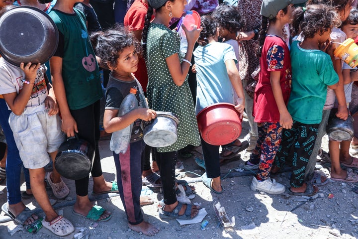 Palestinian children stand in line with their pots at a food distribution point in the northern Gaza's Jabalia refugee camp on August 21, 2024.