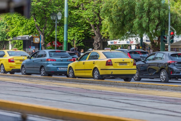 Yellow taxi on the road of Athens, sign of TAXI on yellow vehicle