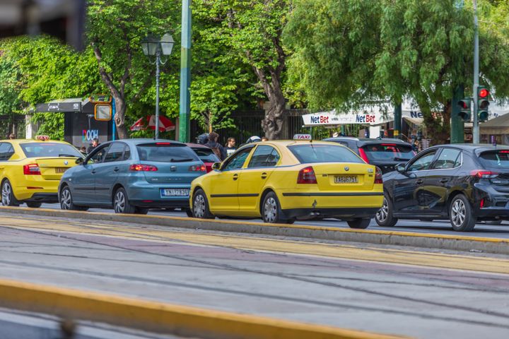 Yellow taxi on the road of Athens, sign of TAXI on yellow vehicle