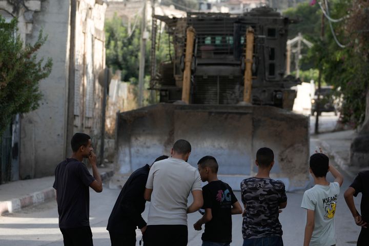 Palestinian children stand in front of an Israeli bulldozer during an army raid in the West Bank city of Jenin.