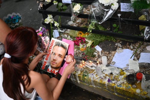 A fan holds a magazine with a photo of Payne as she pays tribute to him outside the hotel where he died in Buenos Aires, Argentina.