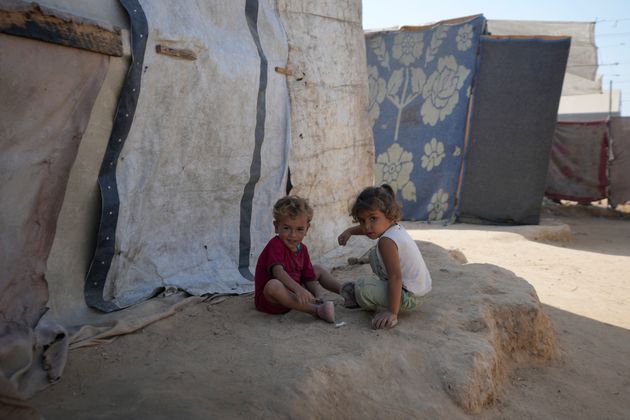 Displaced Palestinian children sit next to their tent in Deir al-Balah, Gaza Strip.