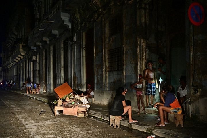 Cubans chat at night on a street during a nationwide blackout caused by a grid failure in Havana on October 18, 2024. Technical breakdowns, fuel shortages and high demand have caused the country's thermoelectric power plants to constantly fail, forcing the government to declare an energy emergency and take measures such as closing schools and factories. (Photo by Adalberto ROQUE / AFP) (Photo by ADALBERTO ROQUE/AFP via Getty Images)