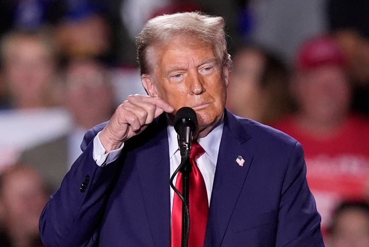 Former President Donald Trump taps the microphone as the audio goes out during a campaign event in Detroit, on Friday, Oct. 18, 2024.