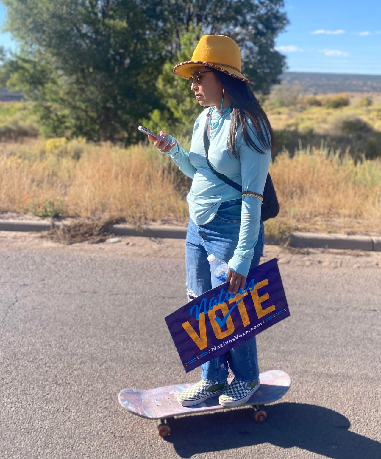 A young Indigenous woman skateboards through the Walk to the Polls event, bound for a polling center in Fort Defiance, Arizona.