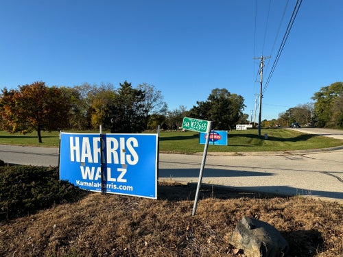 At the entrance of the IUPAT District Council 7 union hall, a neighbor's Trump sign is visible behind the union's signs for Harris and Sen. Tammy Baldwin (D-Wis.).