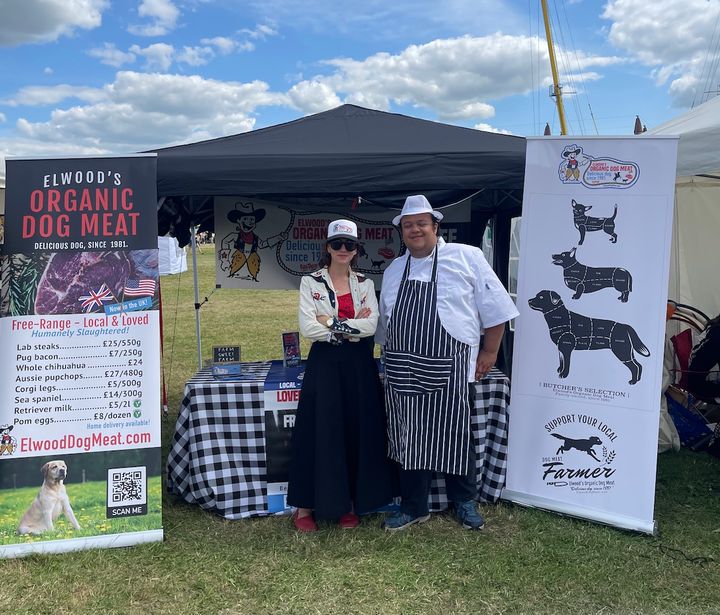 The author (left) and U.K. activist Brooke Linnet in front of Elwood’s Organic Dog Meat booth at Vegan Campout in Oxfordshire in August. 