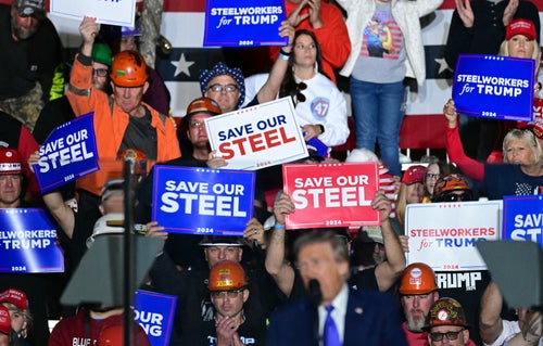 Supporters hold "Save our Steel" signs as former US President and Republican presidential candidate Donald Trump speaks behind bulletproof glass during a campaign rally at Arnold Palmer Regional Airport in Latrobe, Pennsylvania, a swing state.