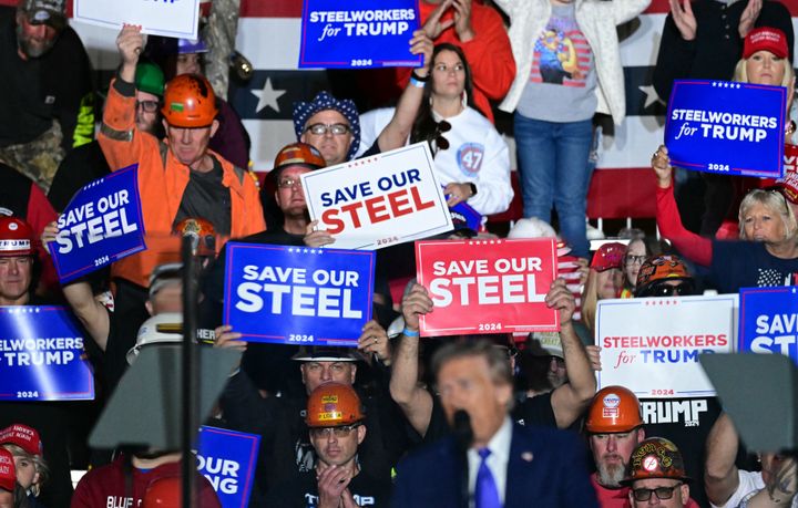 Supporters hold "Save our Steel" signs as former US President and Republican presidential candidate Donald Trump speaks behind bulletproof glass during a campaign rally at Arnold Palmer Regional Airport in Latrobe, Pennsylvania, a swing state. 