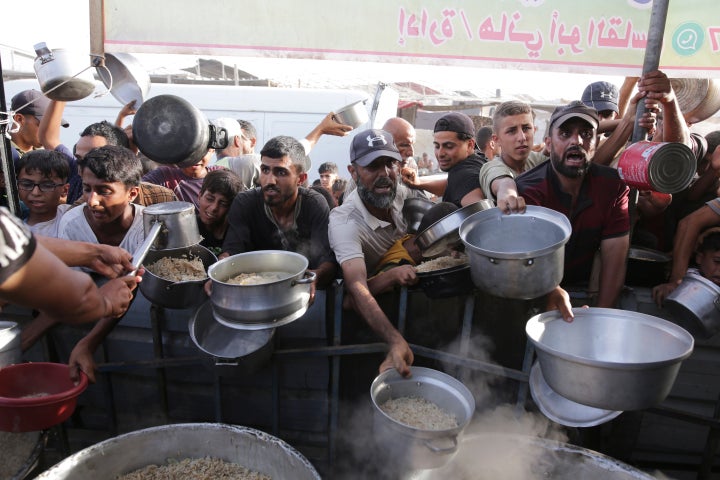 Palestinian men collect food aid ahead of the Eid al-Adha holiday in Khan Younis, Gaza Strip, on June 15, 2024.