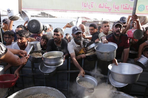 Palestinian men collect food aid ahead of the Eid al-Adha holiday in Khan Younis, Gaza Strip, on June 15, 2024. 