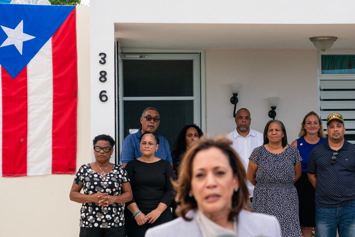 Bewohner beobachten von ihrem Balkon aus, wie Vizepräsidentin Kamala Harris spricht, nachdem sie am 22. März 2024 ein Privathaus in Canovanas, Puerto Rico, besichtigt hat.