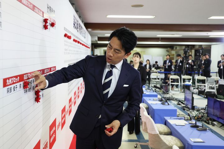 候補者名に花を付ける小泉選対委員長（10月28日、東京・永田町）。与党が過半数割れしたことを受け、選対委員長を辞任