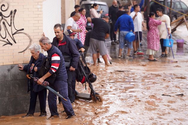 Άνθρωποι περπατούν σε πλημμυρισμένους δρόμους στη Βαλένθια της Ισπανίας, Τετάρτη 30 Οκτωβρίου 2024. (AP Photo/Alberto Saiz)