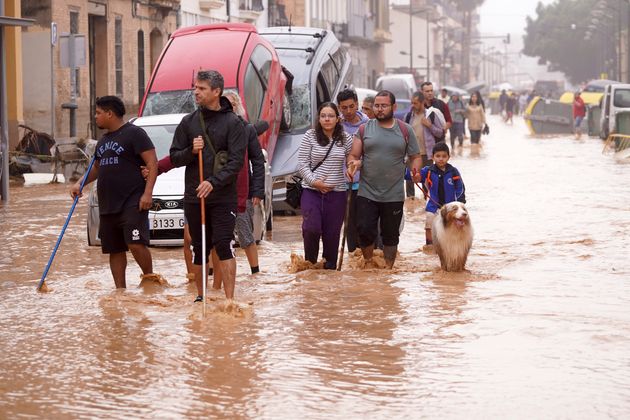 Άνθρωποι περπατούν σε πλημμυρισμένους δρόμους στη Βαλένθια της Ισπανίας, Τετάρτη 30 Οκτωβρίου 2024. (AP Photo/Alberto Saiz)