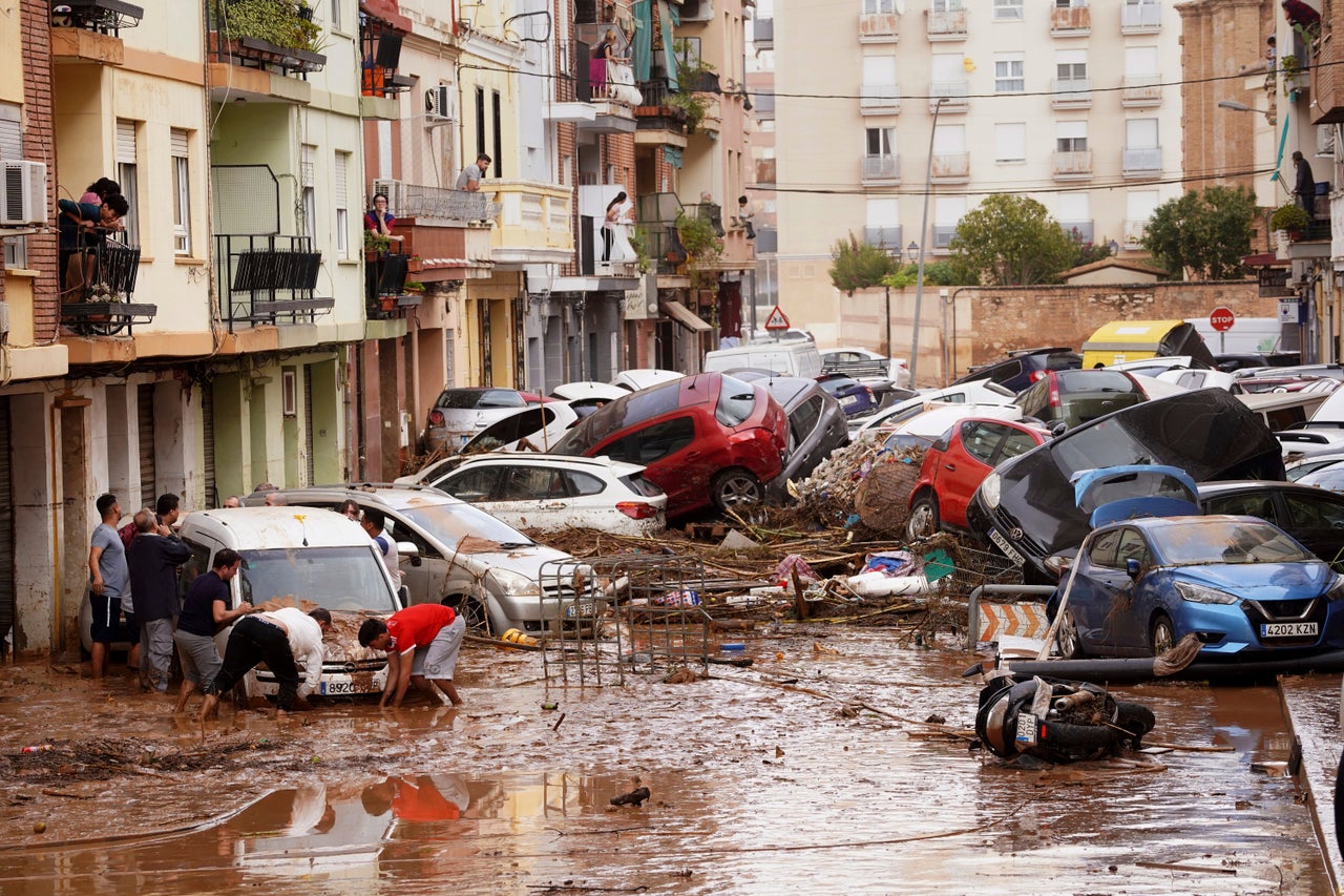 Κάτοικοι βλέπουν τα αυτοκίνητά τους, σε πλημμυρισμένη γειτονιά της Βαλένθια.